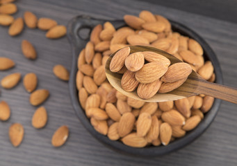 Almonds in wooden bowl and spoon (Prunus dulcis)
