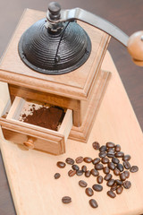 Closeup of coffee grinder and coffee bean on wooden background.