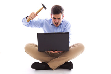 Man sitting on the floor hitting the computer with hammer