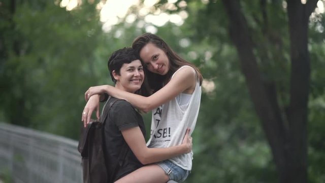 The lesbian sit on a fence and hugs her girlfriend