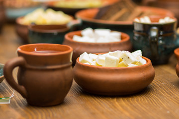 Italian cheese in an earthenware pot diced next to a mug