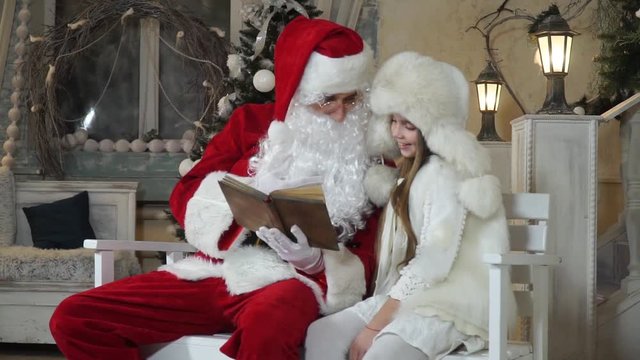 On a bench near the old house Santa reading a book for girls