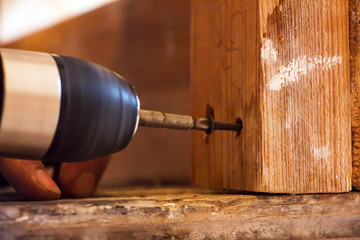 Man Screwing a screw into the wood element by means of the electrical screwdriver 4