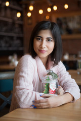Young beautiful woman with Christmas decor sitting in cafe, drinking coffee. Christmas, new year, winter holidays concept. Christmas morning.

