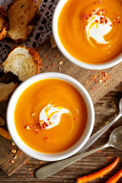 Homemade pumpkin soup in a white ceramic bowl on a wooden rustic table, nutritious and delicious vegetarian dish