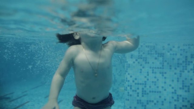 The child learns to swim underwater in the pool