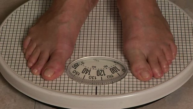 Woman stepping on a bathroom scale