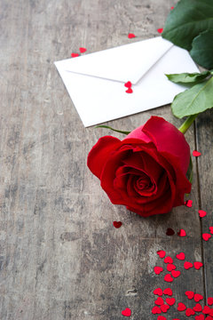 Rose, envelope and hearts on wooden background
