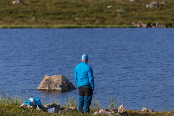 Man in blue clothes standing and looking out over the lake.