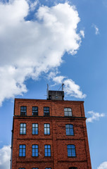 Brick house with blue sky and white clouds in the background.