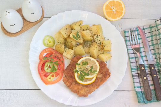 Wiener schnitzel with potatoes in plate on table