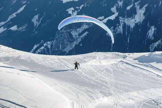 The pilot lands on a paraplane with a mountain-skiing slope of Penken - Mayrhofen, Austria
