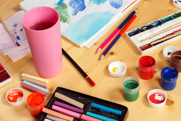 Naklejka premium Different paints and crayons are on the table next to the figure