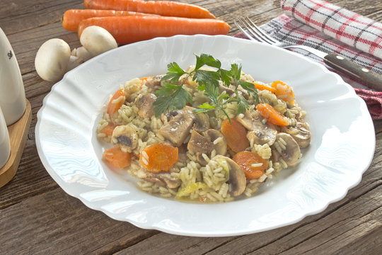 Risotto with mushrooms and vegetables in plate on table