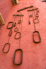 Set of old metal chains hanging on a red wall