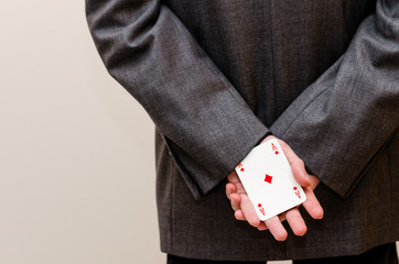 Businessman holding an ace card in his hands, hidden behind him