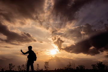 Silhouette man with backpack use smartphone in hands at sunset b