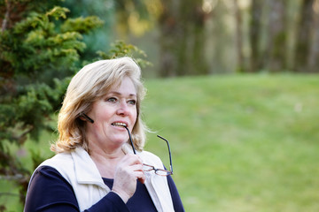 Woman thinking while talking on the phone, absentmindedly chewing on glasses