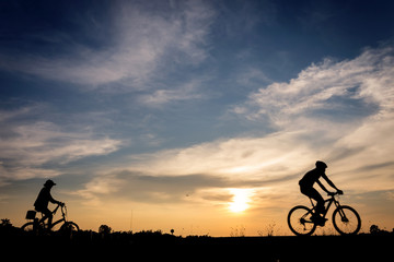 Silhouette of cyclist with friend in motion on the background of