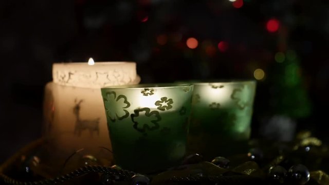 three beautiful candles on background of flashing Christmas tree