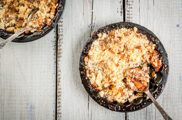 Freshly baked crumble with berries and apples on a white wooden table, copy space