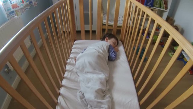 Young toddler in his crib falling to sleep. Filmed in a time lapse shot.