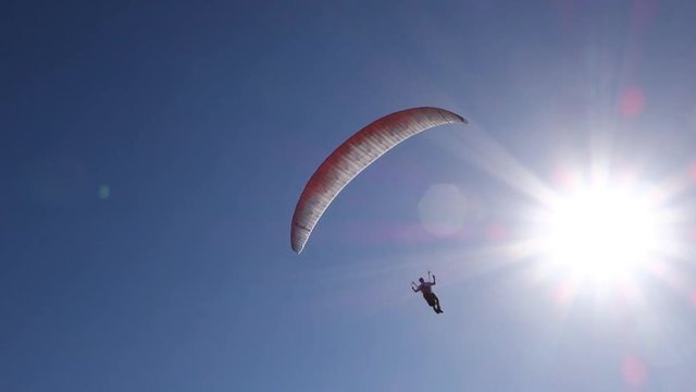 Paraglider flies into the summer sunlight. Nice flare.