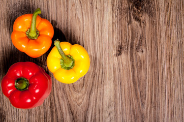 Three home peppers on wood table background. Sweet paprika in Kitchen.