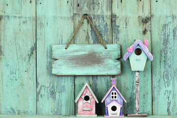 Blank wood sign hanging over birdhouses