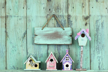 Blank mint green sign hanging over colorful spring birdhouses