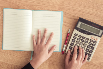 female hands working notebook and calculator