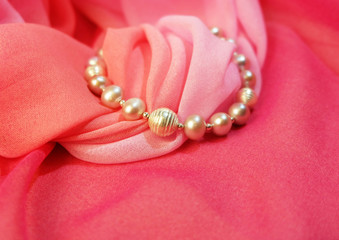 Bracelet from pearls against the background of pink fabric.