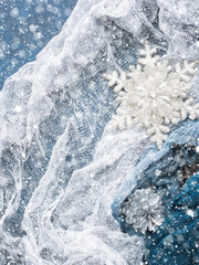 Fototapeta premium Winter christmas background with snow flake and silver textile. Top view. Vertical. Snow falling