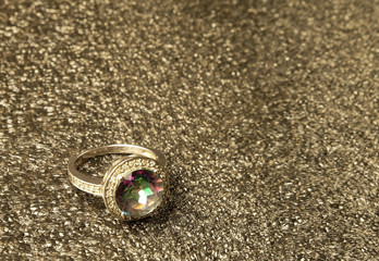 Ring with the mystic topaz on the gray poured background.