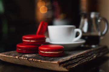 Macaroons with cup of coffee on wood plate, blur in background