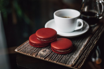 Macaroons with cup of coffee on wood plate, blur in background