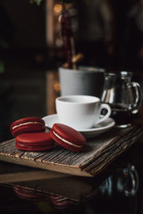Macaroons with cup of coffee on wood plate, blur in background