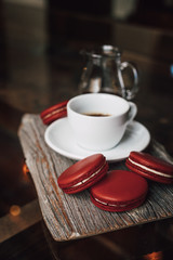 Macaroons with cup of coffee on wood plate, blur in background