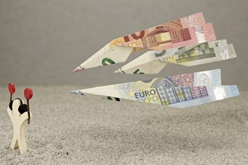 Fluglotse dirigiert Flugzeuge in Form von fliegenden Geldscheinen