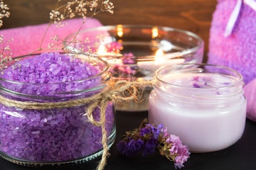 Obraz na płótnie Canvas Spa products. Lavender bath salts, dry flowers, cosmetic cream, light candles and towel. Violet purple concept. Coloring and processing photo.