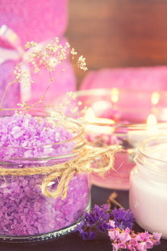 Spa products. Lavender bath salts, dry flowers, cosmetic cream, light candles and towel. Violet purple concept. Coloring and processing photo.