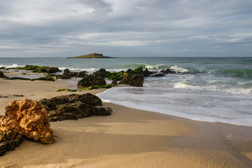 A rock formation in the shore of an isolated beach.