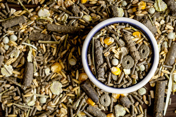 dry food for rodents in bowl wooden background top view