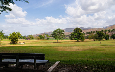 Part of a bench with a wide field in the background.