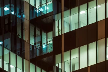 Stickers pour porte construction de la ville Skyscraper windows glow at night. Modern office building at night