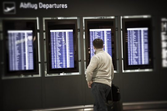 Unrecognizable person looking at Departures board in an airport