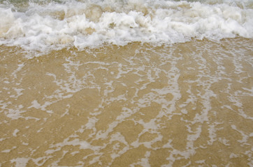 blurred and selective focus image of wave hitting the beach