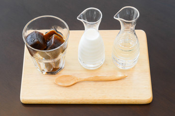 Ice coffee in ice-cube shape with steam milk and syrup on wooden