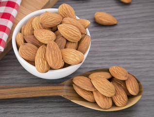 Almonds in white bowl on wooden background