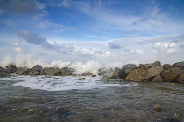 blurred and selective focus image of wave hitting breakwater on